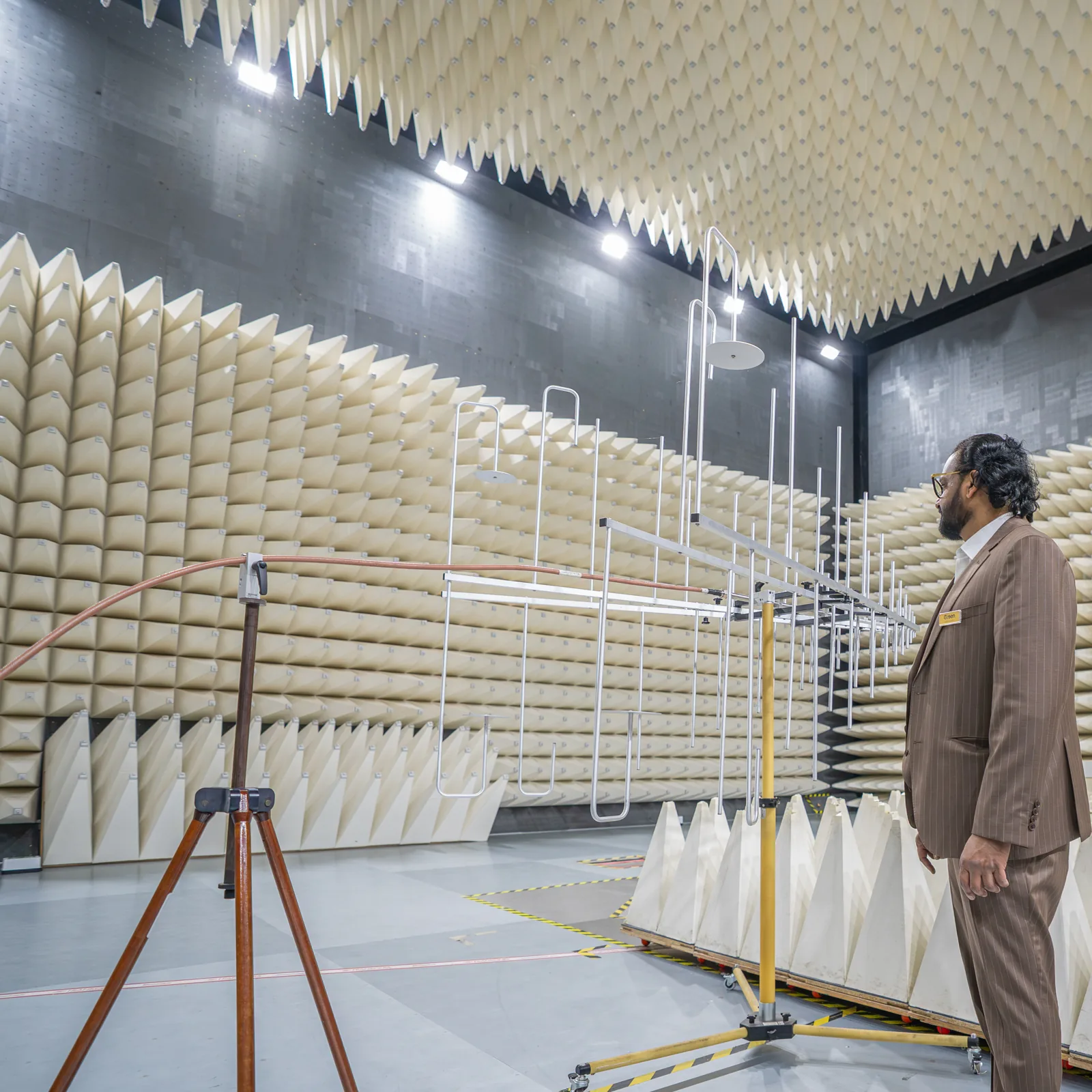 Managing Director Shafiulla H N beside the antenna array and the tripod holding its cable in the anechoic chamber