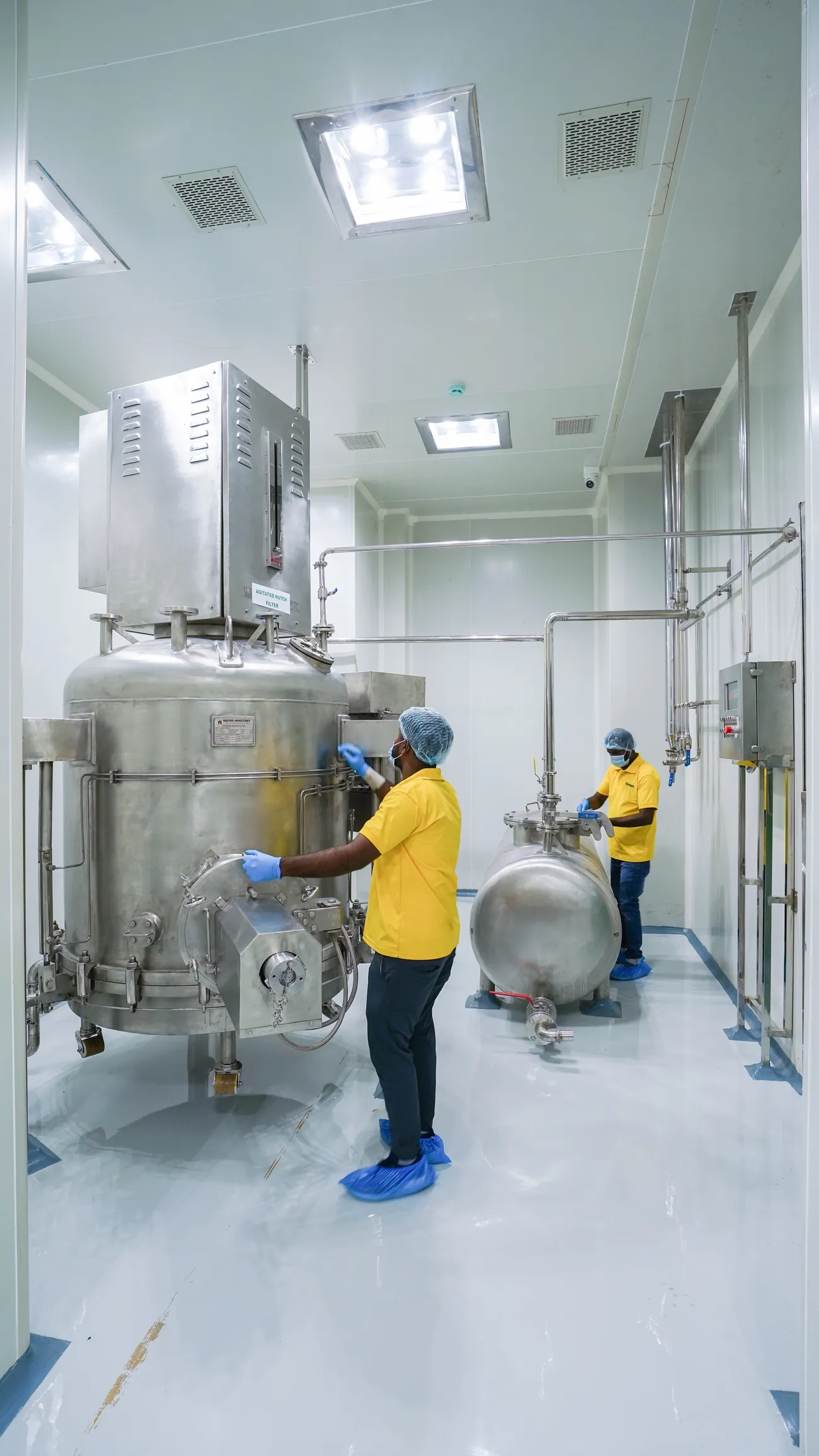 Two operators at stainless reactor vessels in a cleanroom