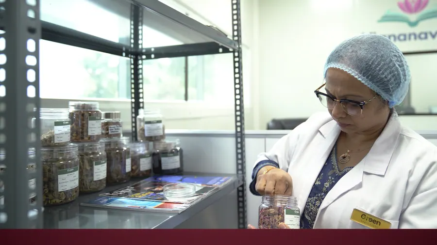 A scientist taking a reference sample from the herbarium shelves