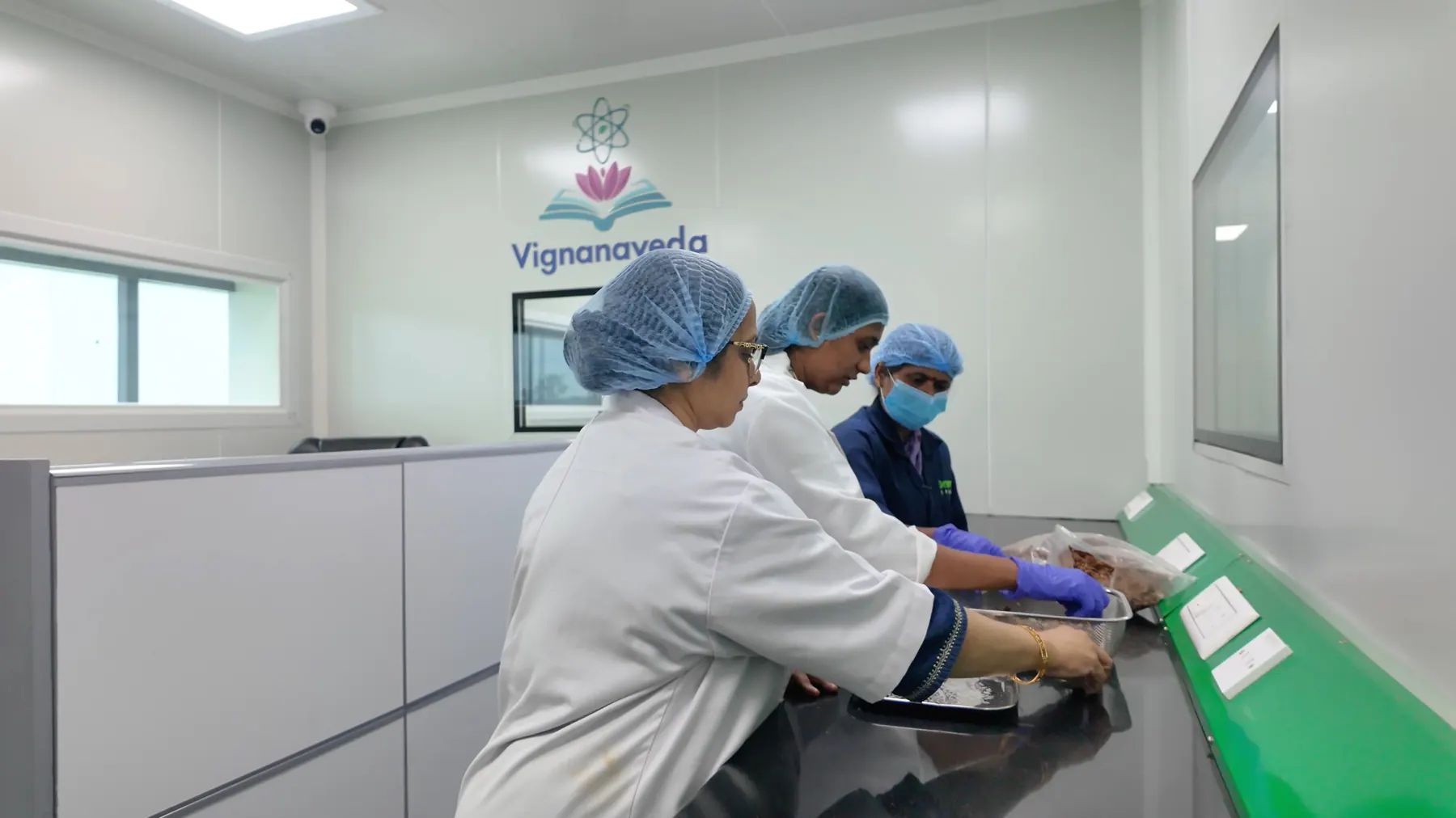 Vignanaveda scientists at the laboratory bench, the Vignanaveda mark on the wall