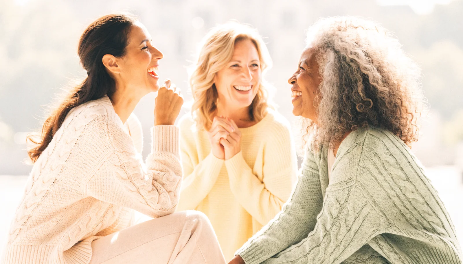 Three generations of women laughing together outdoors